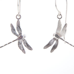 A pair of silver dragonfly shaped earrings hanging from silver earring hook wires